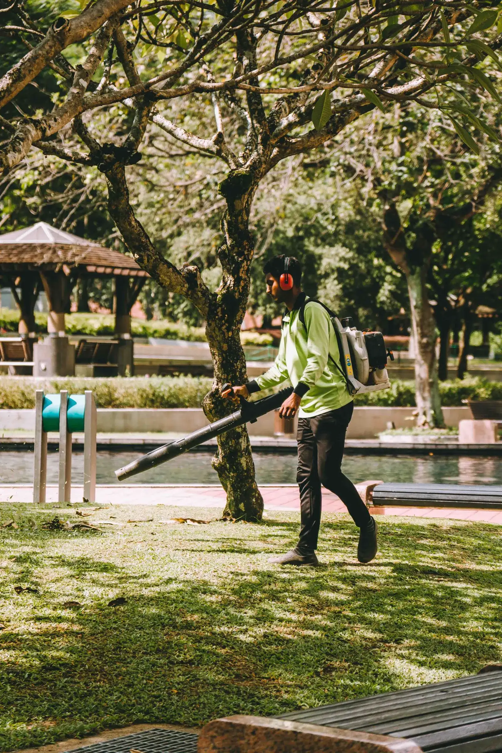 A worker clearing fallen leaves with a leaf blower